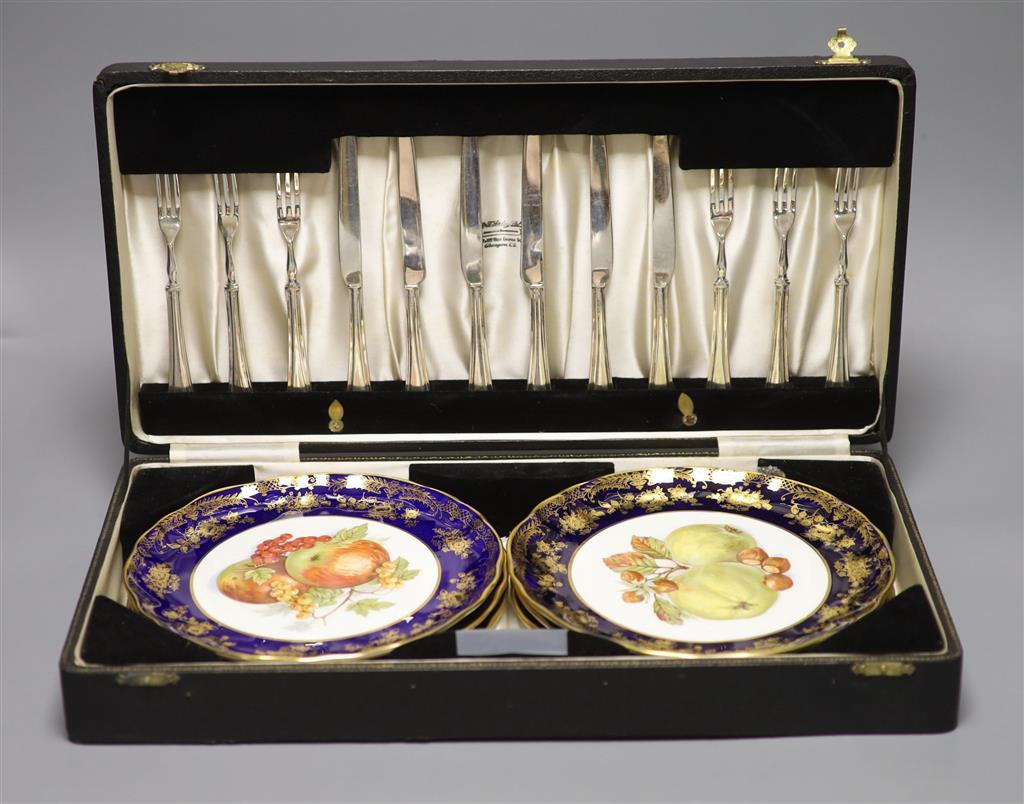 A cased dessert service containing six gilt and fruit decorated plates and a set of knives and forks